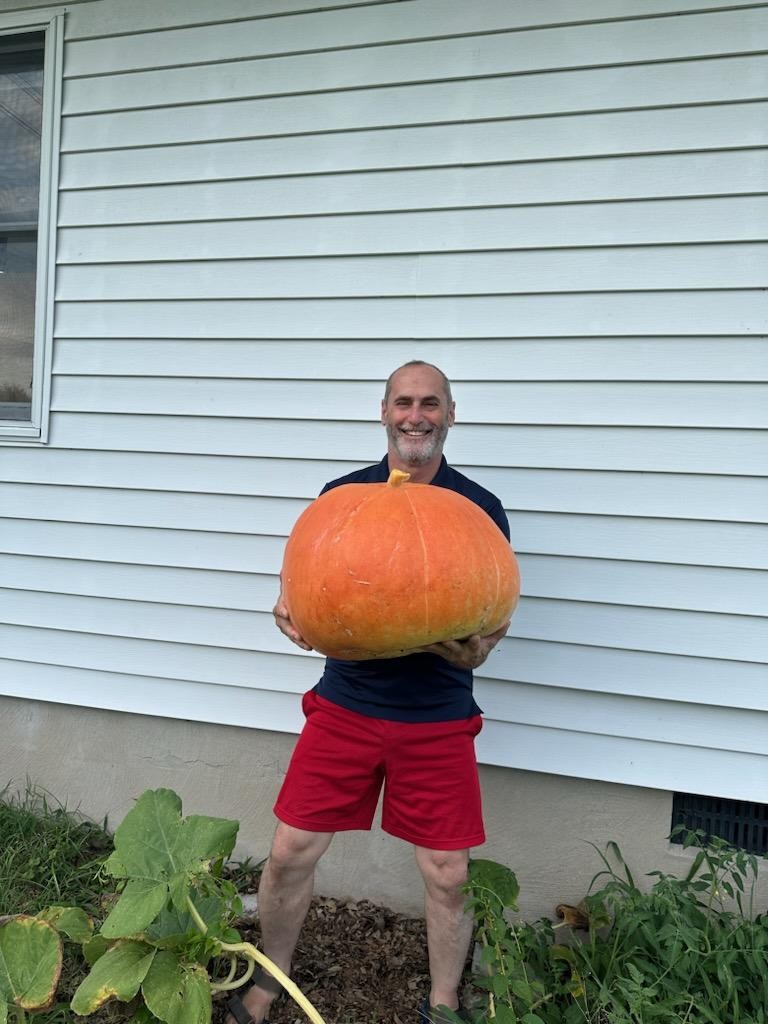 Mark Carroll holding a giant pumpkin grown at Scuttlebutt Farm